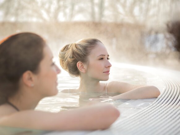Zwei Frauen genießen ihre Winter-Auszeit im warmen Thermalwasser