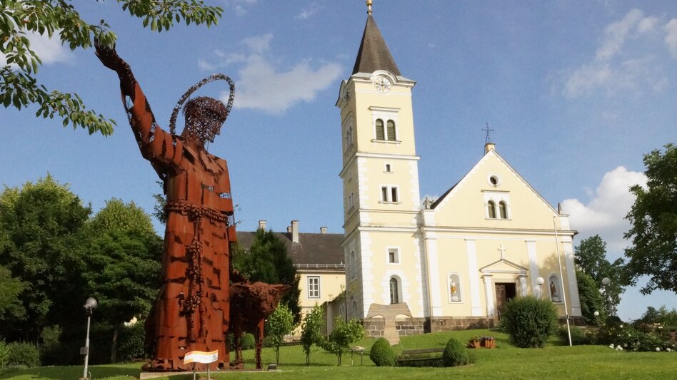 Kirche und Edelstahl-Statue am Marktplatz in Tieschen