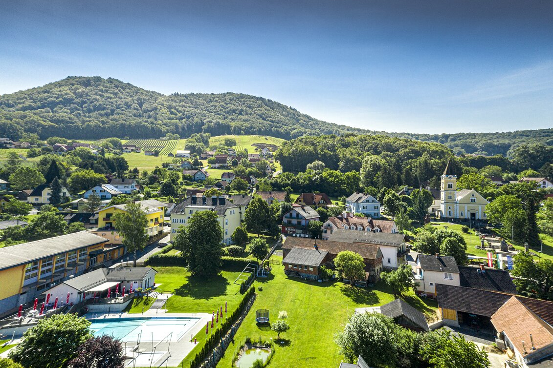 Luftaufnahme von Tieschen mit Pfarrkirche, Freibad und grünen Weinbergen