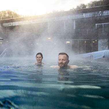 Woman & man swim in the steaming thermal water of the Therme der Ruhe in Bad Gleichenberg