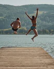 Zwei Personen springen vom Steg in den Stubenbergsee in der Oststeiermark
