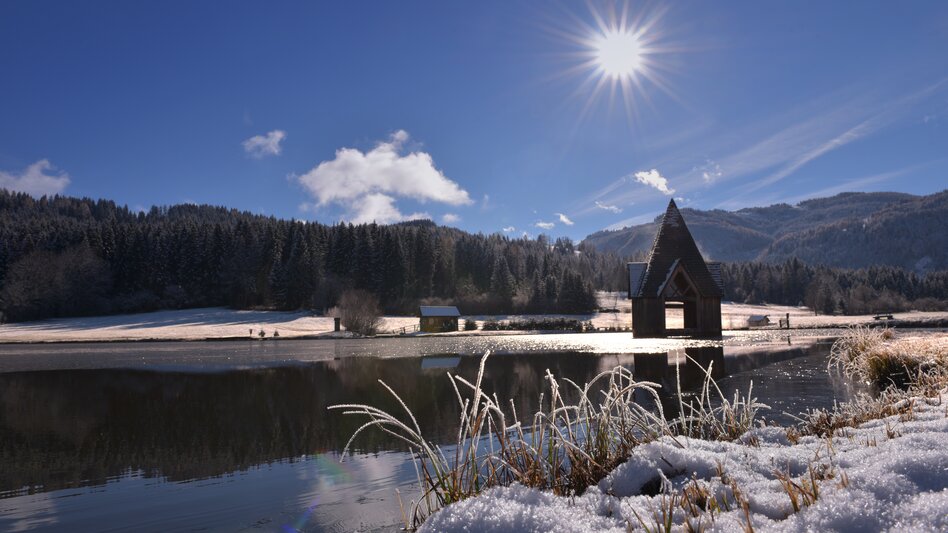 verschneiter Teich mit Holzturm