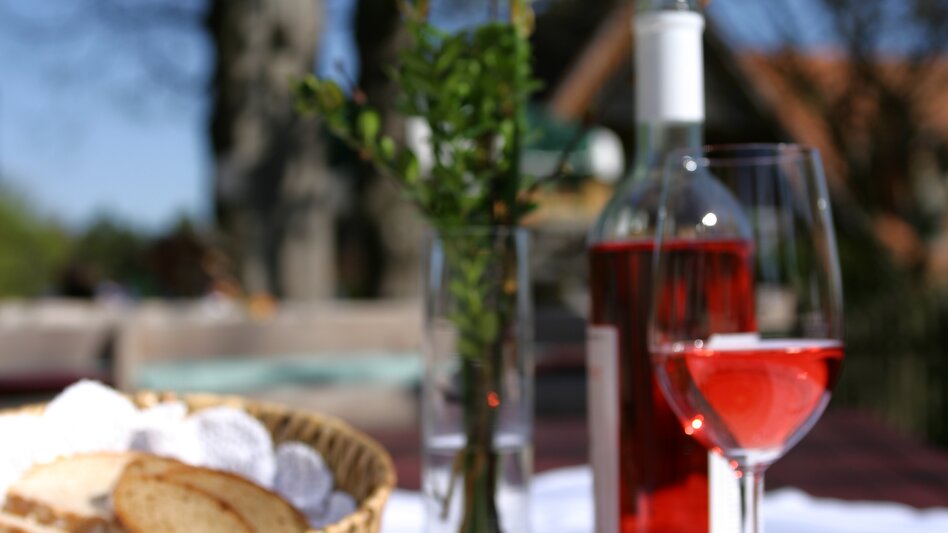 Eine klassische Sulze mit einem guten Glas roséfarbenen Schilcher bei Sonnenschein im Buschenschank-Garten