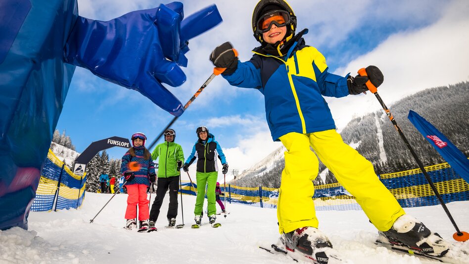 Familie fährt am Präbichl die Funslope hinunter, die abgegrenzt von den anderen Skipisten ist.