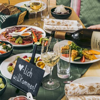Jemand schenkt Wein ein zum Buffet am Tisch im Buschenschank Schneeberger | © Buschenschank Schneeberger