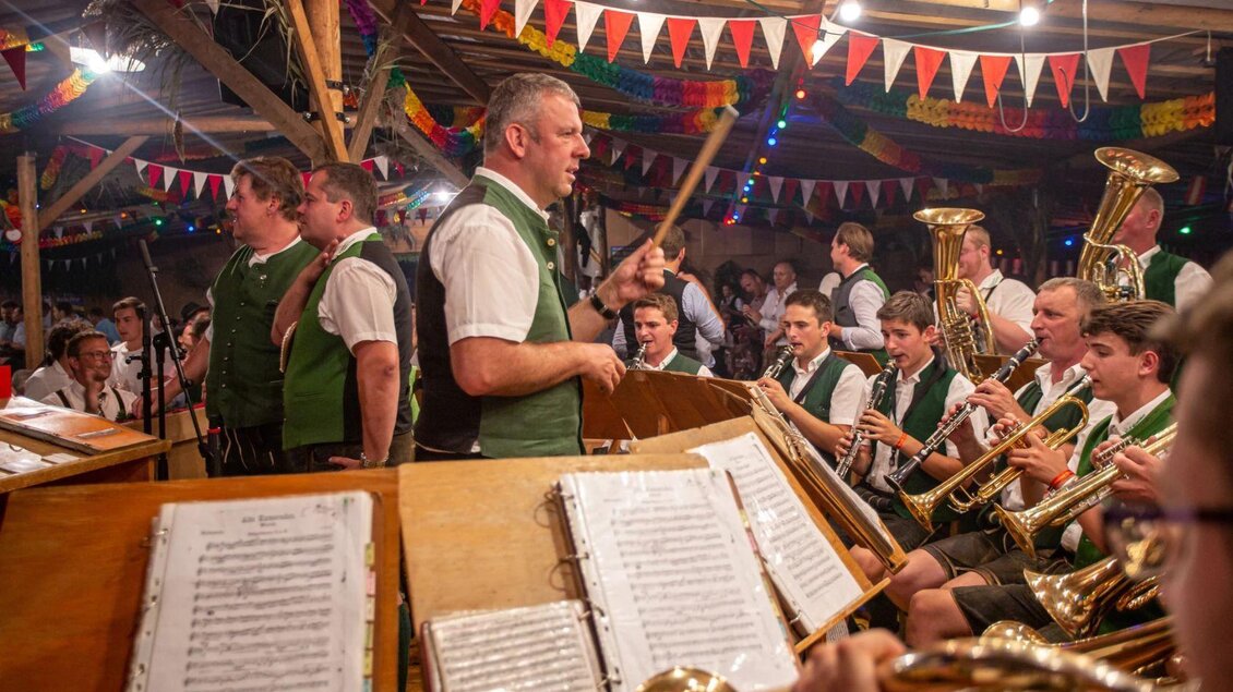 Eine livige Musikveranstaltung mit einer Blaskapelle in traditionellen Trachten. Die Atmosphäre ist festlich dekoriert mit bunten Girlanden und Lichtern. | © Freiwillige Feuerwehr Altaussee