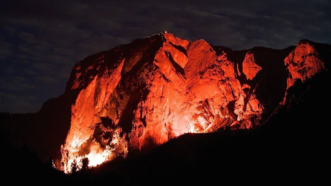 Eine beeindruckende Berglandschaft in der Nacht, beleuchtet von orangefarbenem Licht. Die Felsen wirken stark und dramatisch in der Dunkelheit. | © Fremdenverkehrsverein Altaussee