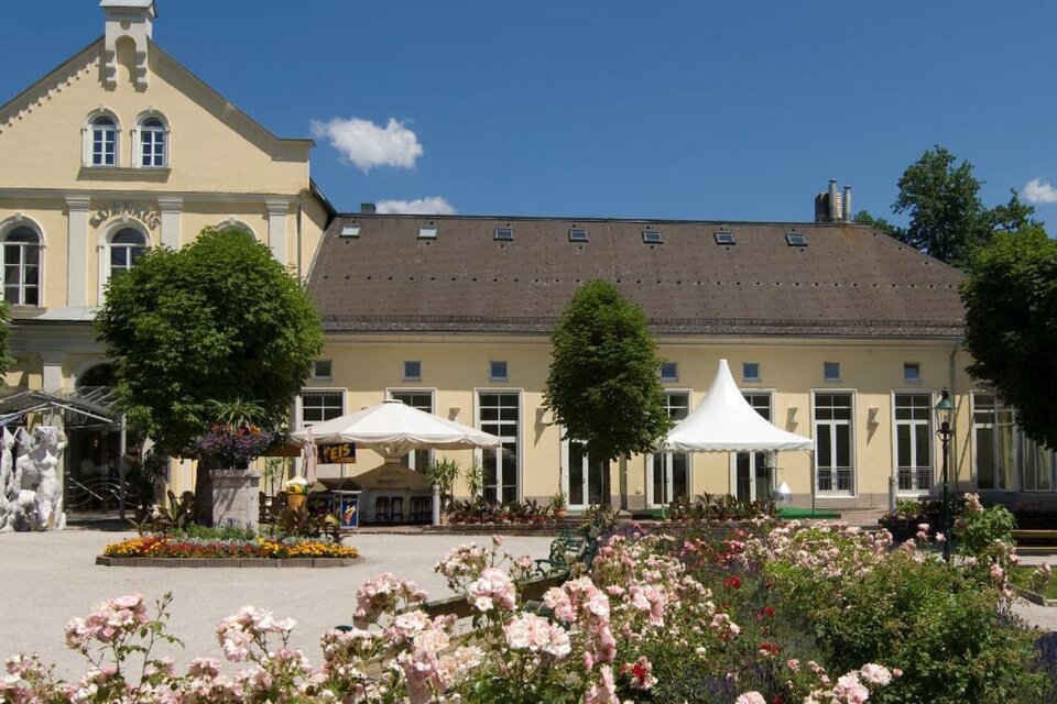 Ein schön angelegter Garten mit blühenden Blumen und einem historischen Gebäude im Hintergrund. Pavillons und Sonnenschirme laden zum Verweilen ein. | © TVB Ausseerland Salzkammergut_Rastl