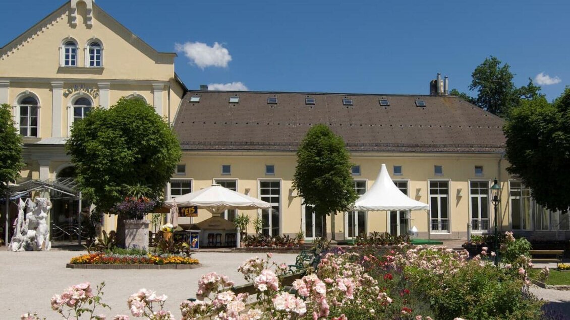 Ein schön angelegter Garten mit blühenden Blumen und einem historischen Gebäude im Hintergrund. Pavillons und Sonnenschirme laden zum Verweilen ein. | © TVB Ausseerland Salzkammergut_Rastl