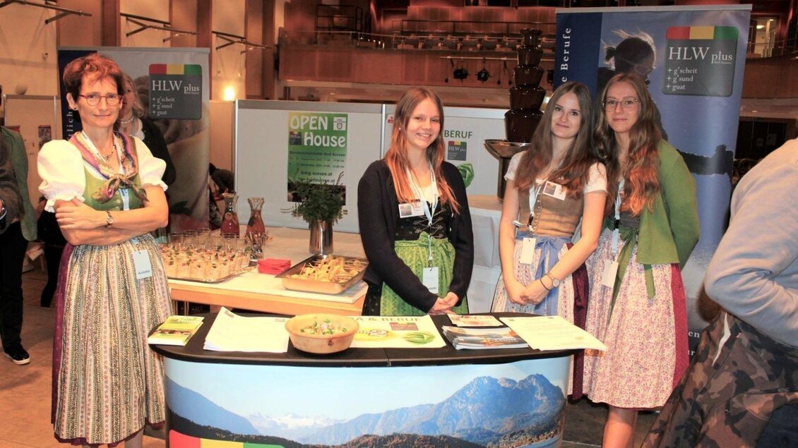<p>Eine Lehrerin mit drei Schülerinnen betreuen den Stand der HLWplus Bad Aussee. Sie tragen Tracht und informieren genauestens über die HLW.</p> | © Arbeitsmarktservice Liezen, www.ams.at
