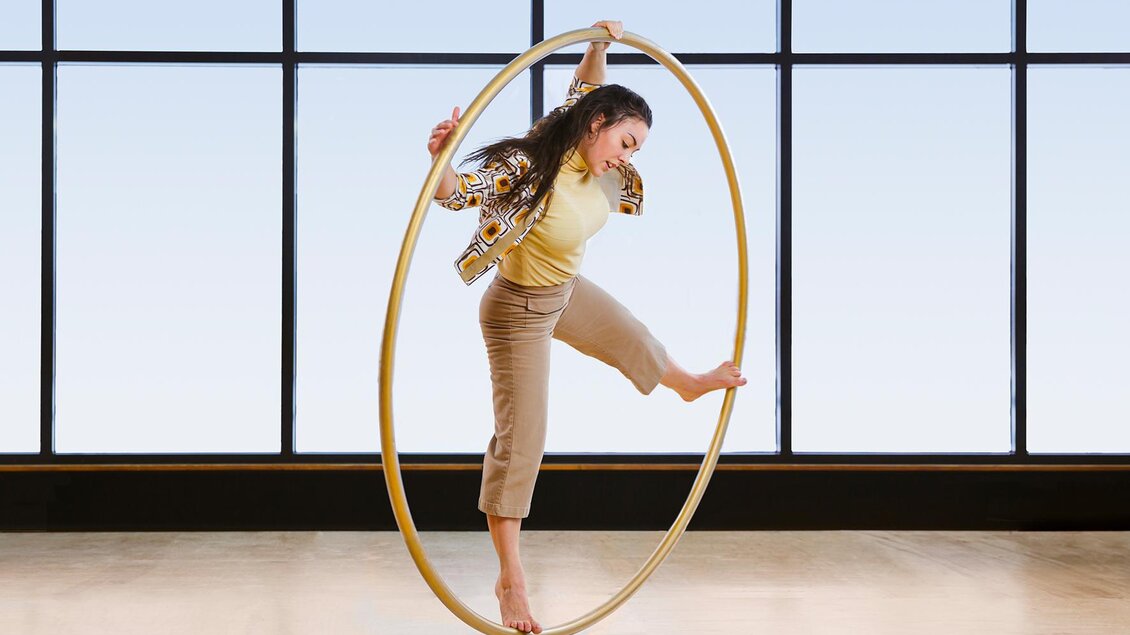 Eine Artistin in heller Kleidung macht kreisende Bewegungen in einem großen Reifen, im Cirque Noël in Graz. | © Emmanuel Burrie