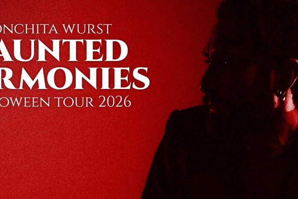 Ein dunkel gekleideter Mann wird vor einem roten Hintergrund gezeigt. DerText kündigt die "Haunted Harmonies" Halloween Tour 2026 von Conchita Wurst an. | © conchitawurs