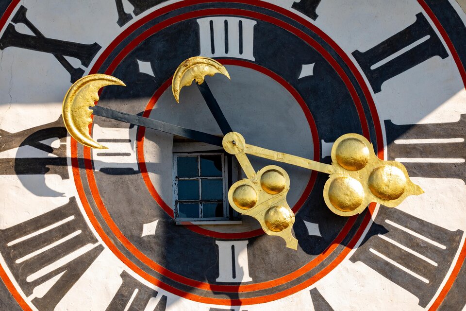Eine große, goldene Uhr mit einem auffälligen Ziffernblatt und auffälligen Zeigern. Im Hintergrund ist eine Wand zu sehen, die die Uhr umgibt. | © (c) Graz Tourismus - Harry Schiffer