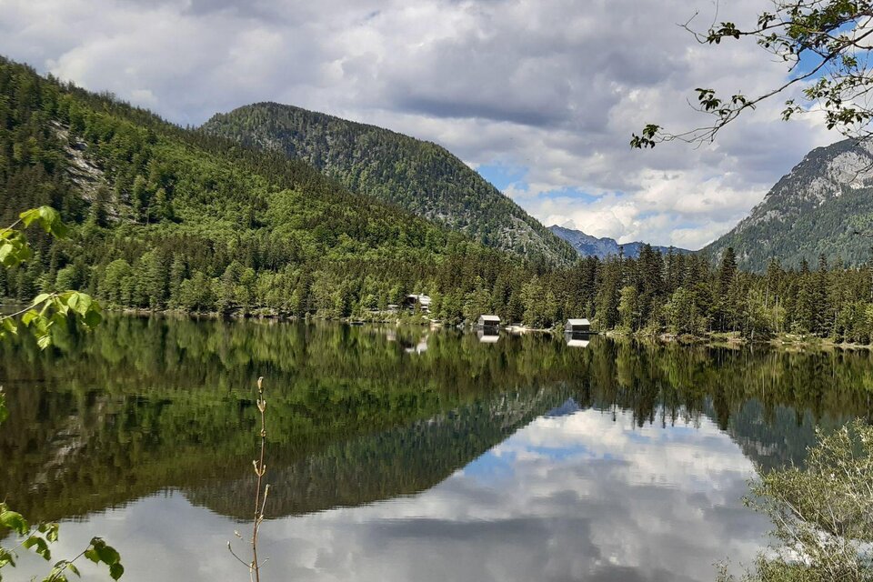 Im klaren Wasser des Ödensees spiegeln sich die beeindruckende Bergkulisse des Ausseerlandes und zwei idyllische Bootshütten. | © Daniela Casari