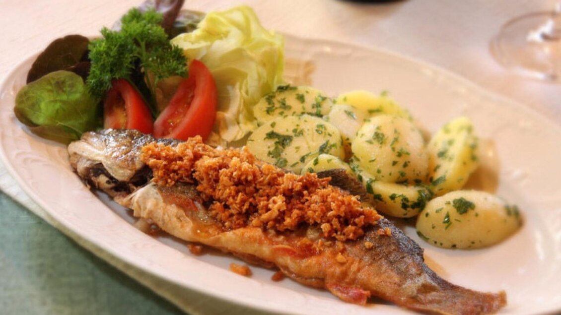 <p>Ein köstlicher Fisch mit knuspriger Parnier, serviert mit Kartoffeln und frischem Salat der Fischerhütte am Toplitzsee.</p> | © Syen Andreas