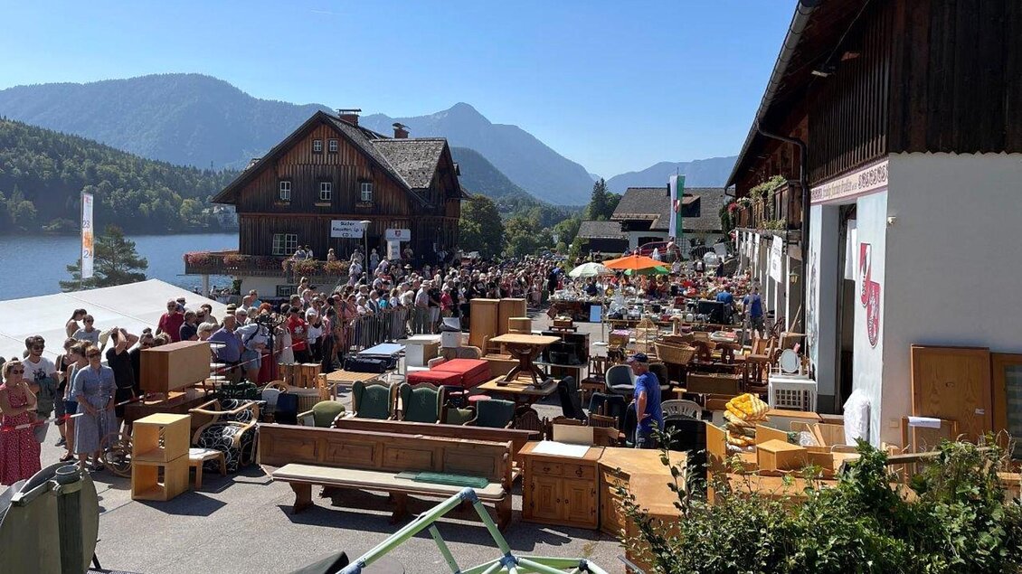 Ein Flohmarkt am Ufer eines Sees mit vielen Ständen und Möbeln. Zahlreiche Menschen sind in der Schlange und genießen das sonnige Wetter. | © FF Grundlsee