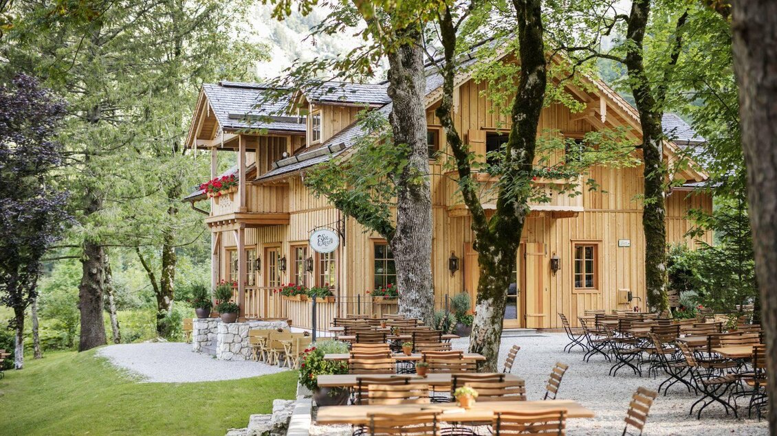 Ein charmantes Holzhaus umgeben von Bäumen. Draußen stehen Tische und Stühle für Gäste. | © Tauroa