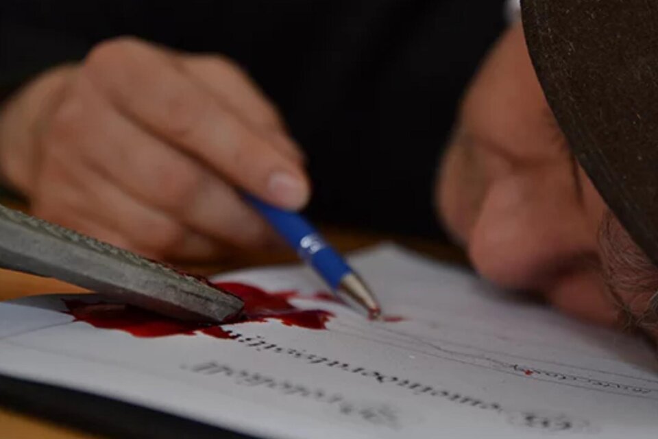 Eine Person liegt auf einem Dokument mit Kulli in der Hand und einem Blutfleck am Papier.  | © engesser marketing GmbH