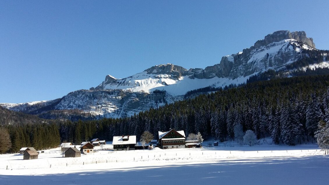 <p>Die verschneite Landschaft der Blaa Alm in Altaussee mit malerischen Almhütten und dem Loser im Hintergrund. Der Wald ist von einer dicken Schneeschicht bedeckt.</p> | © Petra Kirchschlager