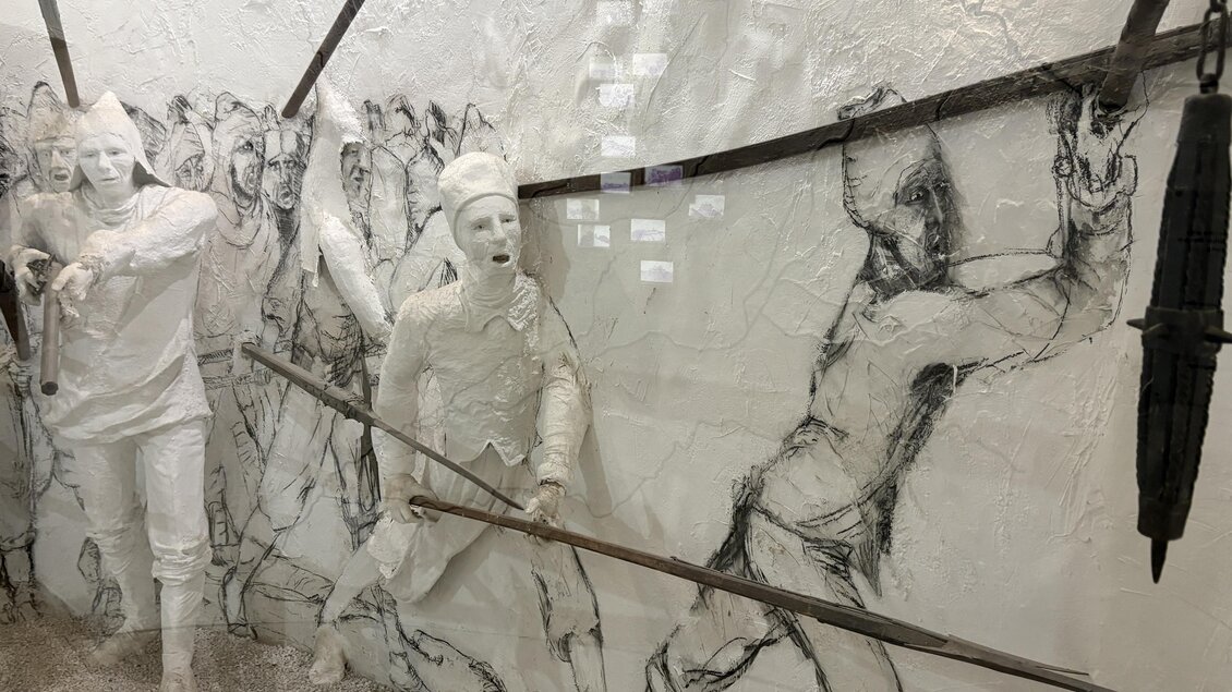 Eine künstlerische Installation mit weißen Figuren, die in Bewegung sind. Im Hintergrund sind skizzierte Figuren und Linien, die eine dynamische Szene darstellen. | © Tourismusverband Thermen- & Vulkanland/Christian Thomaser