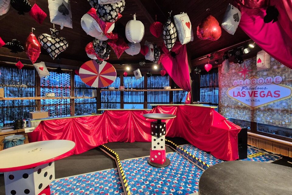 Ein festlich dekorierter Raum im Las Vegas-Stil mit roten und schwarzen Stoffen, großen Würfeln und Spielkarten. Über den Tischen hängen verschiedene Lampions und Dekorationen. | © Jugendverein Grundlsee