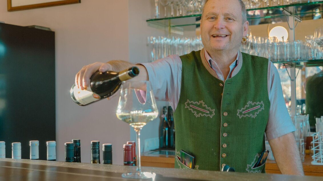 <p>Der Gastwirt Franz bei der Arbeit. Er schenkt freudig ein Glas Weißwein an der Bar ein. </p> | © Elisabeth Pichler