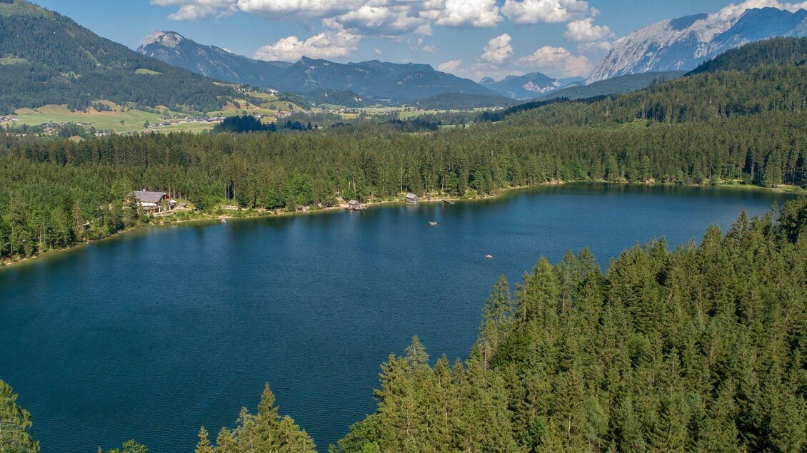 <p>Der ruhige Ödensee kann von oben betrachtet werden. Er ist umgeben von dichten Wäldern und den Bergen des Ausseerlandes. In der Ferne ist auch der Grimming zu sehen. Der Himmel ist klar mit einigen Wolken.</p> | © TVB Ausseerland Salzkammergut/Karl Grieshofer