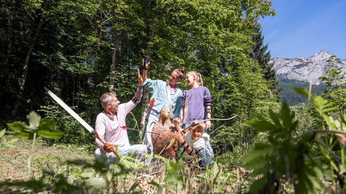 Eine Familie genießt Zeit im Freien, während sie gemeinsam an einem Baum arbeiten. Umgeben von Natur und Bergen wirken sie glücklich und entspannt. | © www.zloam.at