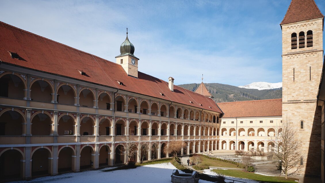 Ein historischer Klosterhof mit einem großen, offenen Innenbereich. Die umliegenden Arkaden und der Glockenturm verleihen der Szene einen malerischen Charakter. | © Wolfgang Spekner