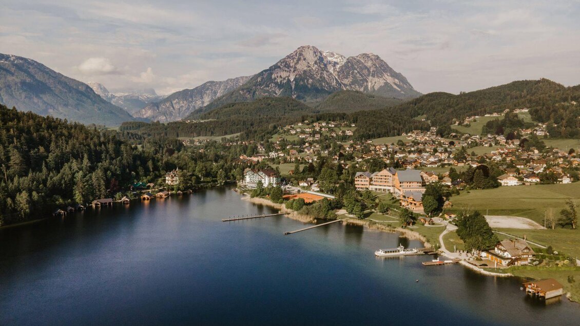 Ein malerischer See umgeben von Bergen und einem kleinen Dorf. Die Landschaft ist grün und einladend, ideal für Erholung in der Natur. | © TVB Ausseerland Salzkammergut_Katrin Kerschbaumer