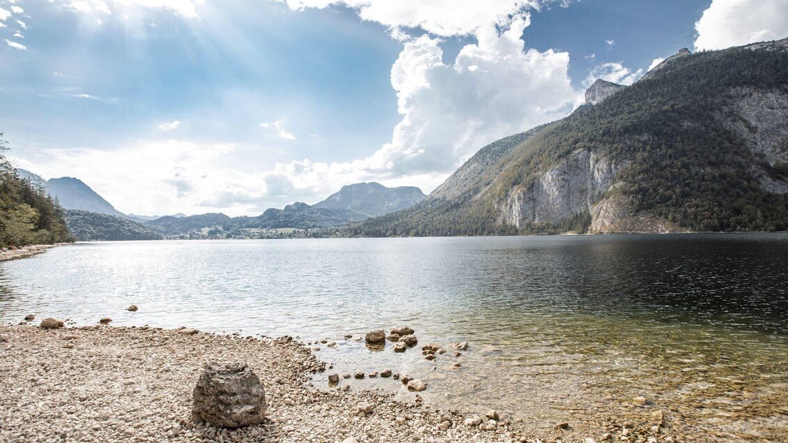 Ein ruhiger See umgeben von Bergen und Bäumen. Der Himmel ist teilweise bewölkt und die Sonne strahlt. | © Oesterreich-Werbung_thecreatingclick-com
