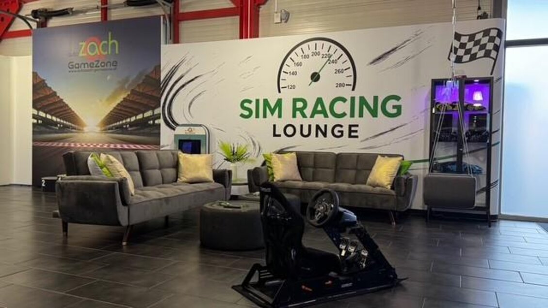 Eine moderne Sim Racing Lounge mit komfortablen Sofas und einem Rennsimulator. Die Wände sind dekoriert mit einem großen Wandbild und Racing-Elementen. | © Thomas Zach