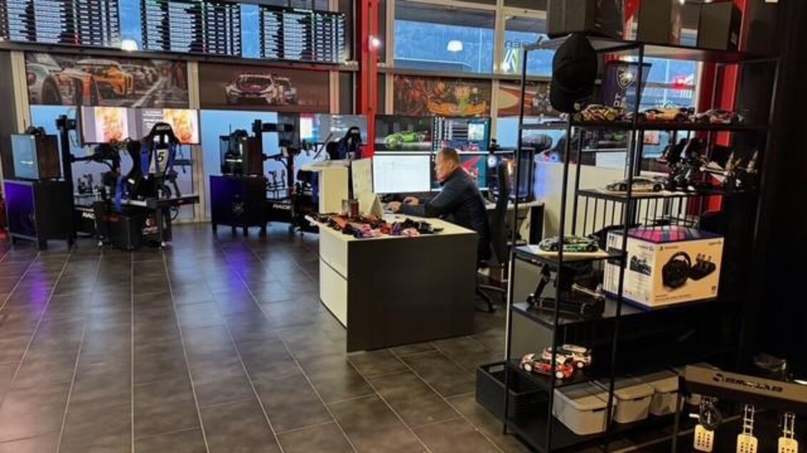 Ein moderner Raum mit mehreren Gaming-Stationen und einem Schreibtisch. Im Hintergrund sind Bildschirme mit Renninformationen zu sehen. | © Thomas Zach