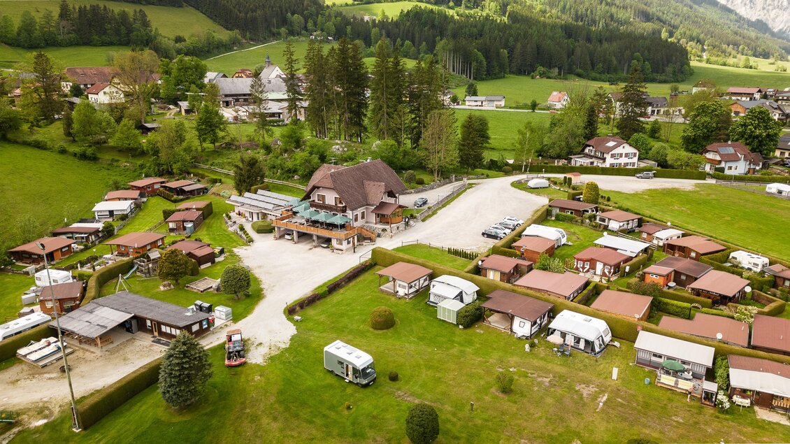 Eine malerische Landschaft mit einem Campingplatz und mehreren Bungalows. Umgeben von grünen Wäldern und sanften Hügeln. | © Hannes Zenz