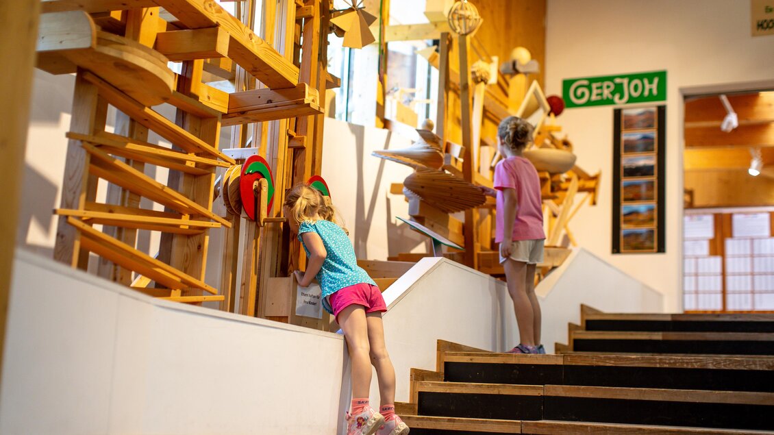 Zwei Kinder erkunden interaktive Holzmechanismen in einem Museum. Sie schauen neugierig auf die verschiedenen Konstruktionen. | © Tourismusverband Murau