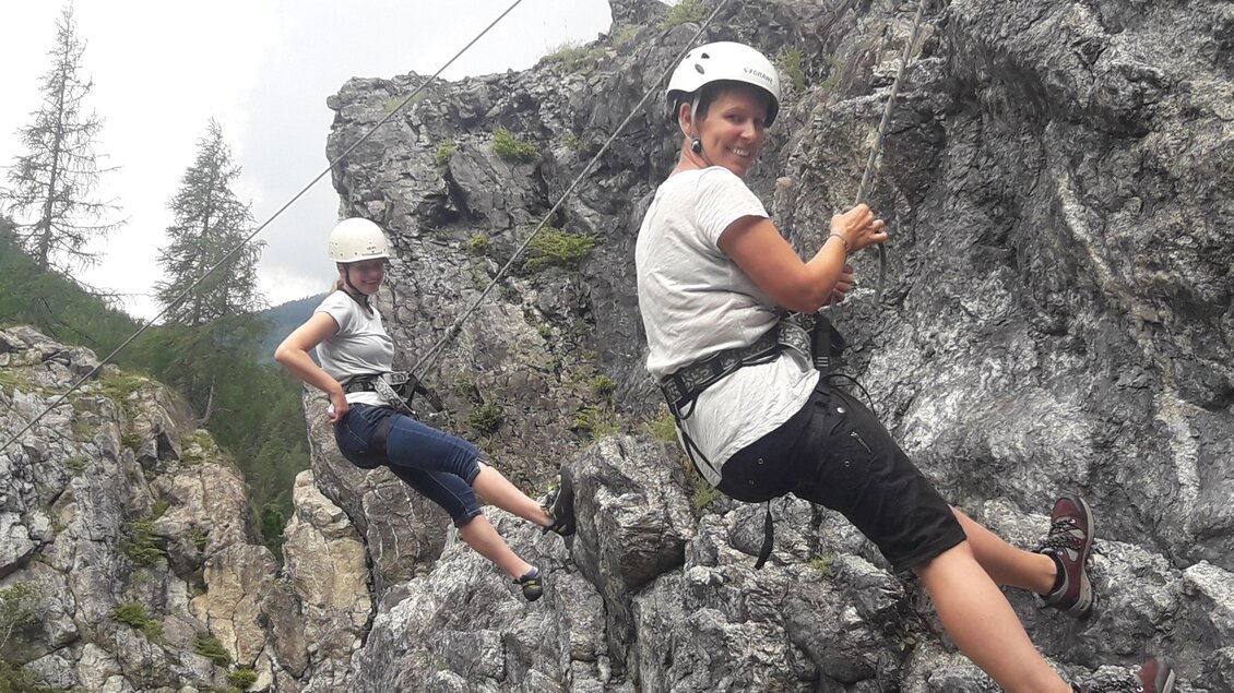 Zwei Personen klettern an einer Felswand und nutzen Sicherheitsausrüstung. Die Umgebung wird von Bergen und Bäumen umgeben. | © Erlebnisregion Murtal