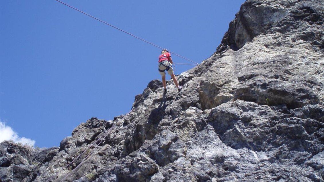 Eine Person klettert an einer steilen Felswand. Der Himmel ist blau mit einigen Wolken. | © Gundula Tackner