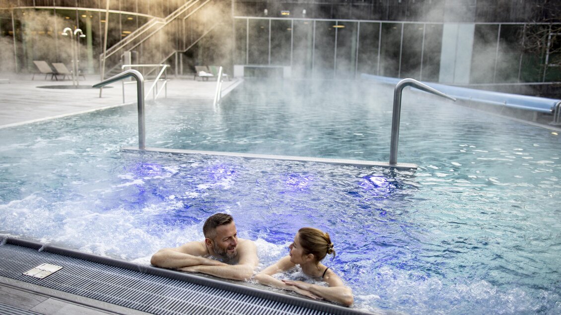 Ein entspannendes Schwimmbad mit dampfendem Wasser. Ein Paar genießt die Ruhe und das Wohlfühlambiente. | © Steiermark Tourismus