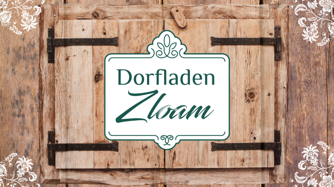 Ein rustikales Schild eines Dorfladens aus Holz. Der Name "Dorfladen Zloam" ist in elegantem Schriftzug dargestellt. | © Narzissendorf Zloam, www.zloam.at