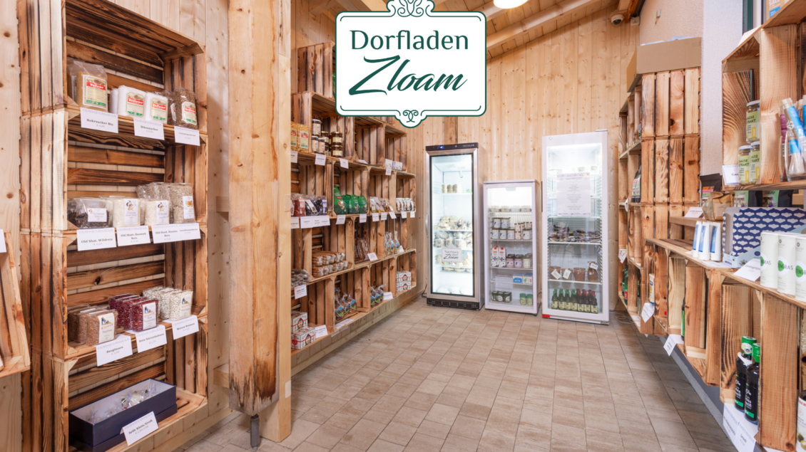 Ein einladender Dorfladen mit Holzbearbeitung und Regalen voller Produkte. Kühlschrank mit Getränken und eine klare, warme Atmosphäre. | © Narzissendorf Zloam, www.zloam.at