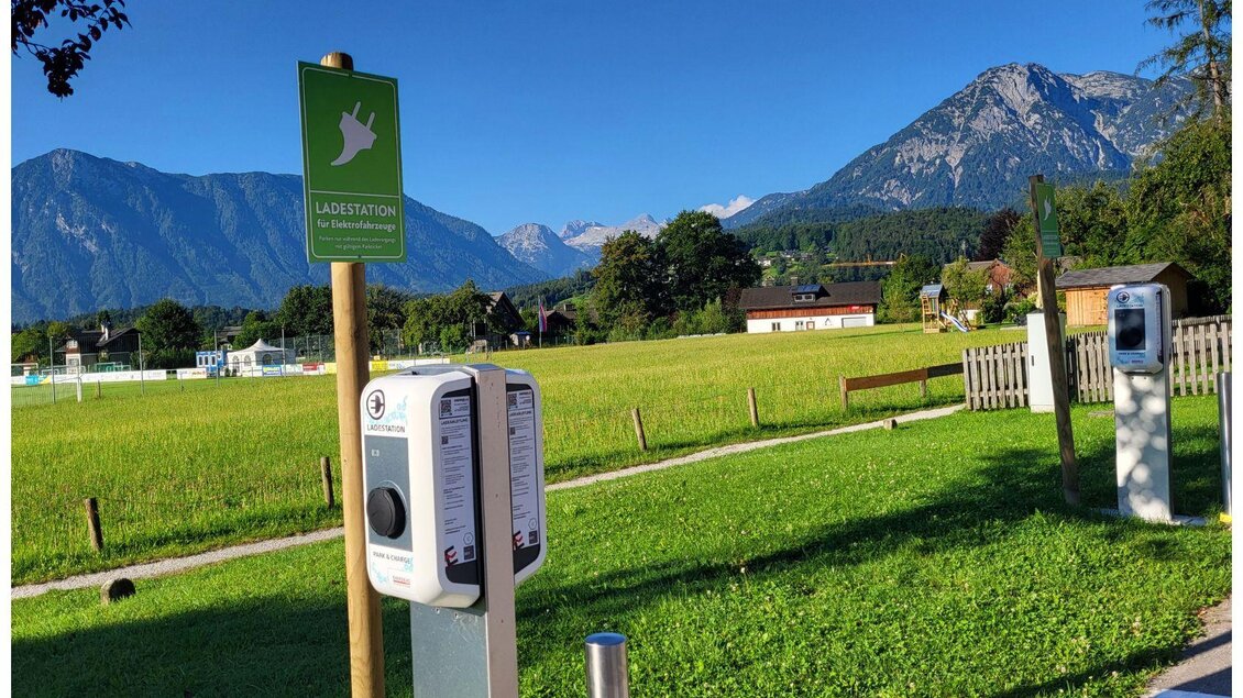 Ein Ladepunkt für Elektroautos in einer ländlichen Umgebung. Im Hintergrund sind grüne Wiesen und Berge zu sehen. | © Petra Kirchschlager