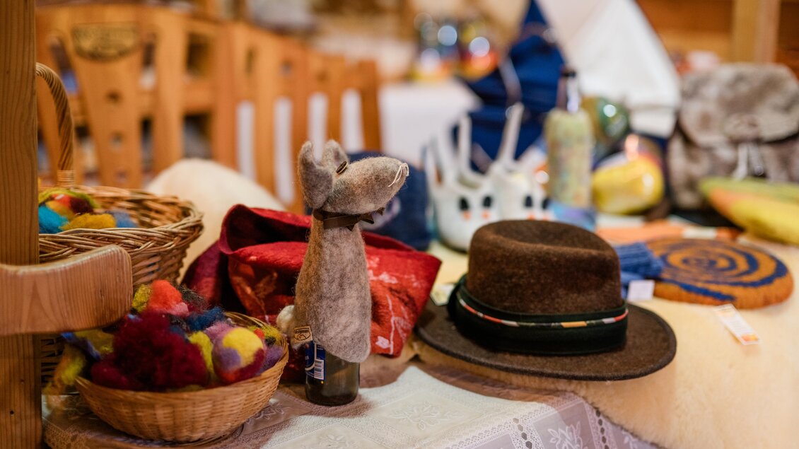 <p>Ein Tisch mit verschiedenen handgemachten Gegenständen, darunter ein Hut, bunte Wollstücke und eine dekorative Figur. Die Atmosphäre ist gemütlich und einladend.Wollgenuss Naturprodukte in Edelsbach bei Feldbach</p> | © vulkanland.atflorphotography