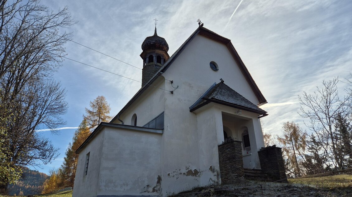 Eine alte Kirche auf einem Hügel, umgeben von Bäumen und klarem Himmel. Der Bau hat einen markanten Turm und zeigt Anzeichen von Verfall. | © Tourismusverband Murau