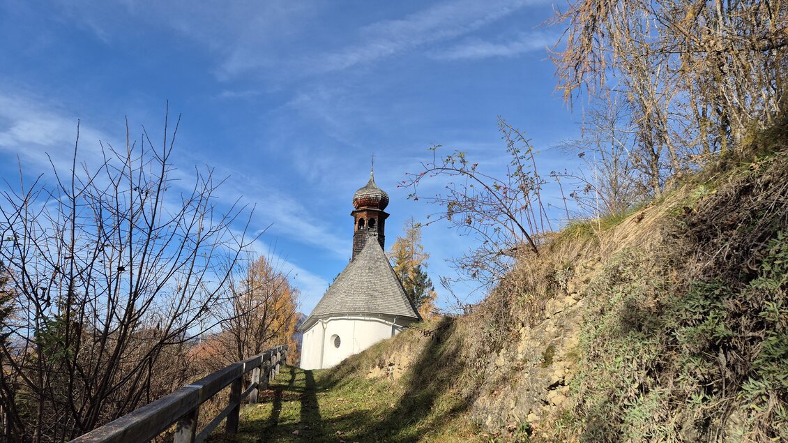 Eine kleine Kapelle steht auf einem Hügel, umgeben von Bäumen und Sträuchern. Der Himmel ist klar und blau, was eine friedliche Atmosphäre schafft. | © Tourismusverband Murau