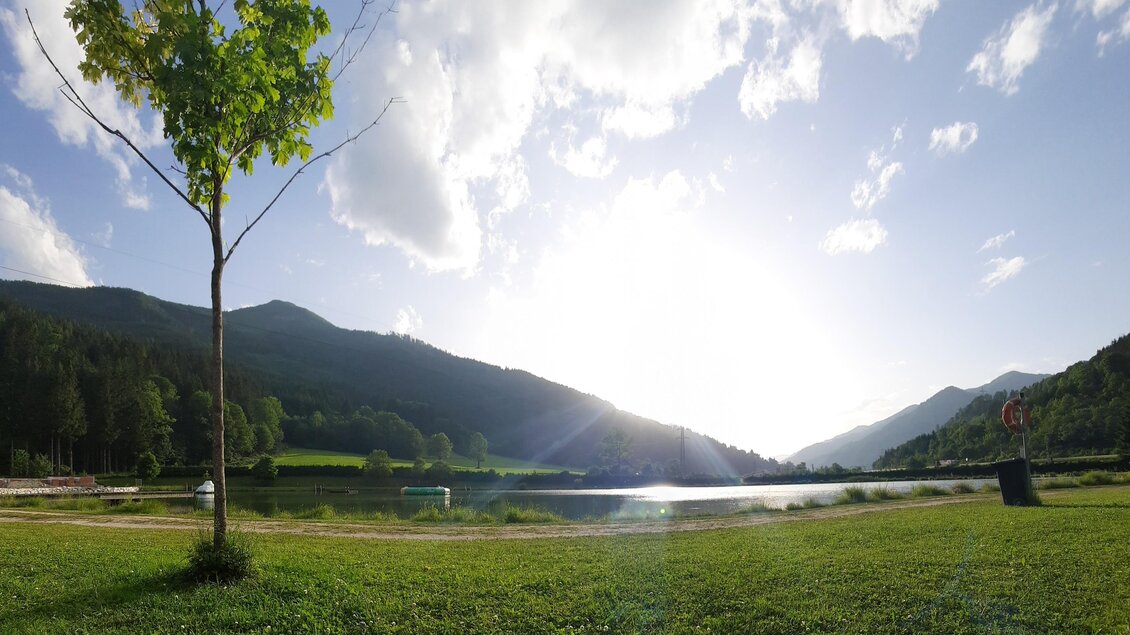 Eine malerische Landschaft mit einem ruhigen See, umgeben von Bergen und sanften Hügeln. Der Himmel ist klar und die Sonne scheint hell. | © Gemeinde Wald am Schoberpaß