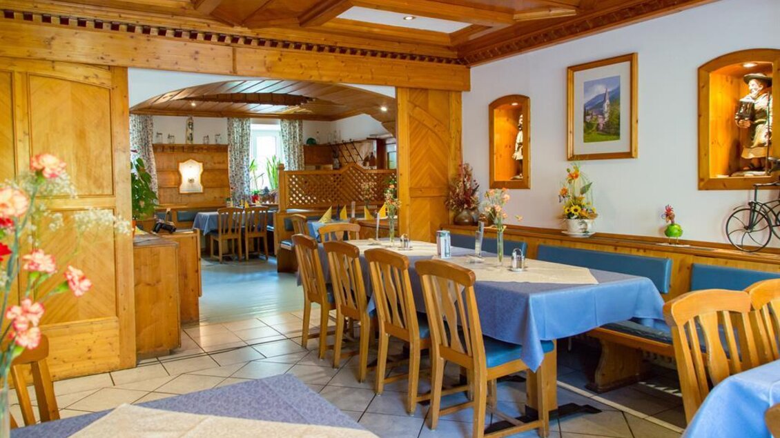 Ein gemütliches Restaurant mit Holzmöbeln und blauen Tischdecken. Die Atmosphäre ist einladend und traditionell. | © Gasthof zum Schwarzen Adler
