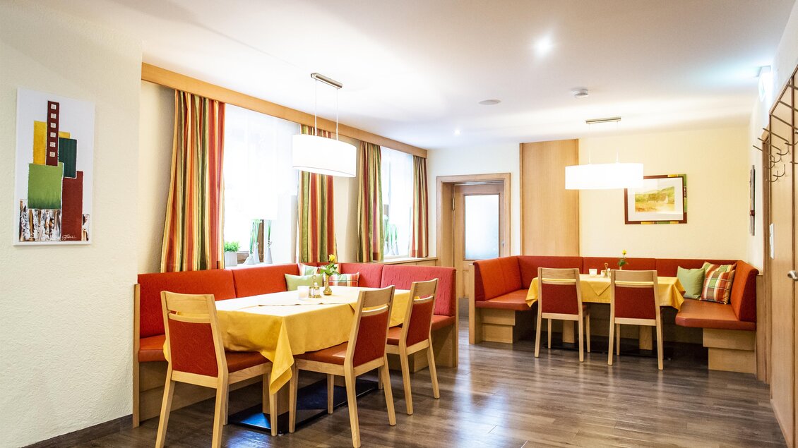 Ein gemütlicher Restaurantbereich mit Holztischen und roten Sitzbänken. Helle Fenster sorgen für eine einladende Atmosphäre. | © Gasthof Landhotel Hubmann