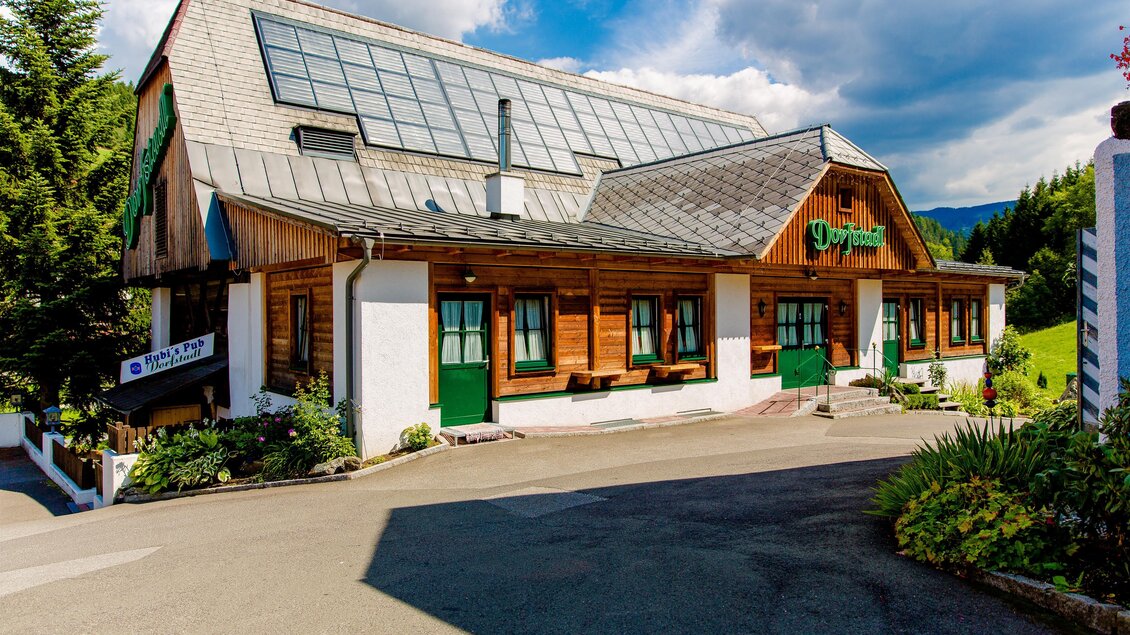 Ein charmantes Gebäude mit Holzelementen und großen Fenstern. Die Umgebung ist grün und lädt zum Verweilen ein. | © Gasthof Landhotel Hubmann