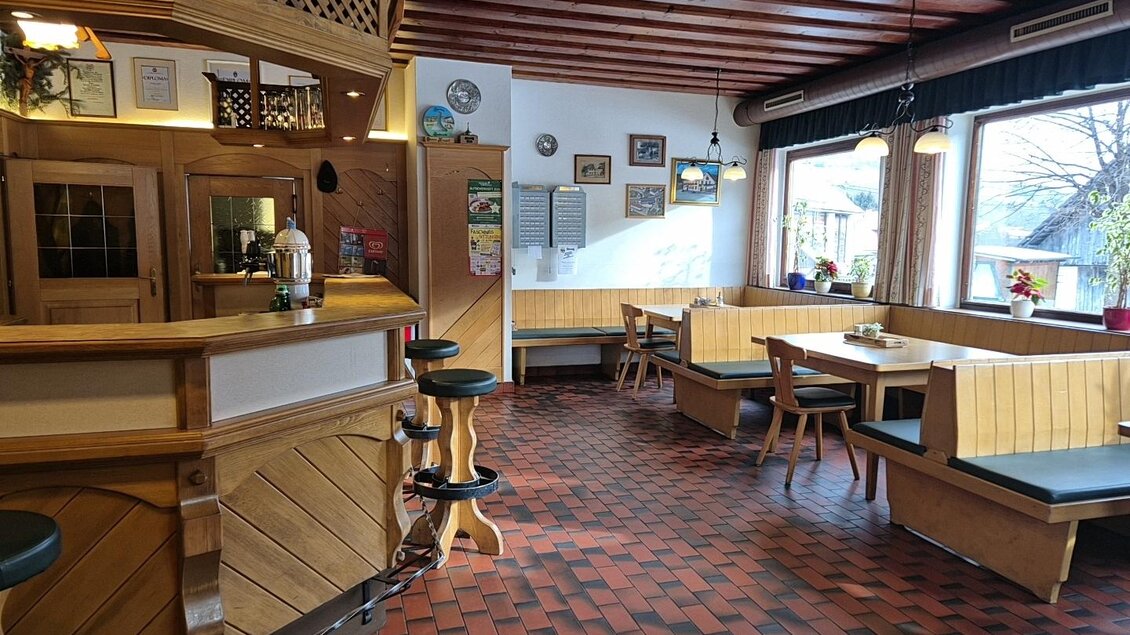 Ein gemütliches Restaurant mit Holzmöbeln und einem einladenden Thekenbereich. Große Fenster sorgen für viel Tageslicht und eine angenehme Atmosphäre. | © TV Murau