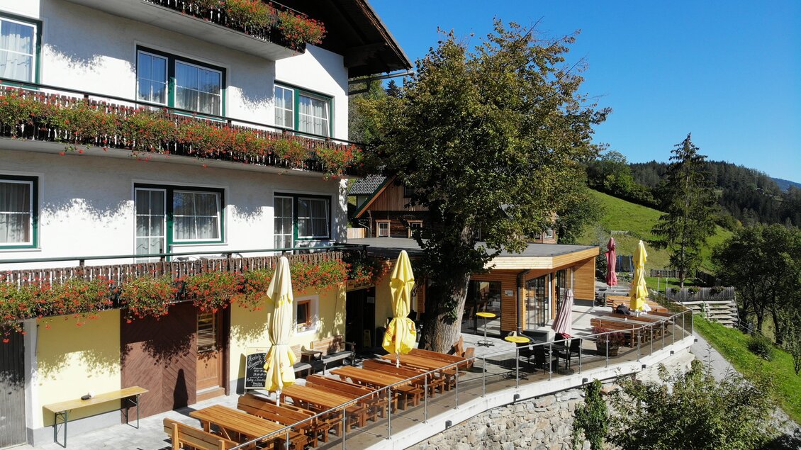 Ein gemütliches Gasthaus mit Terrassenplätzen im Freien. Umgeben von grünen Hügeln und blauen Himmel. | © Gasthof Trattner